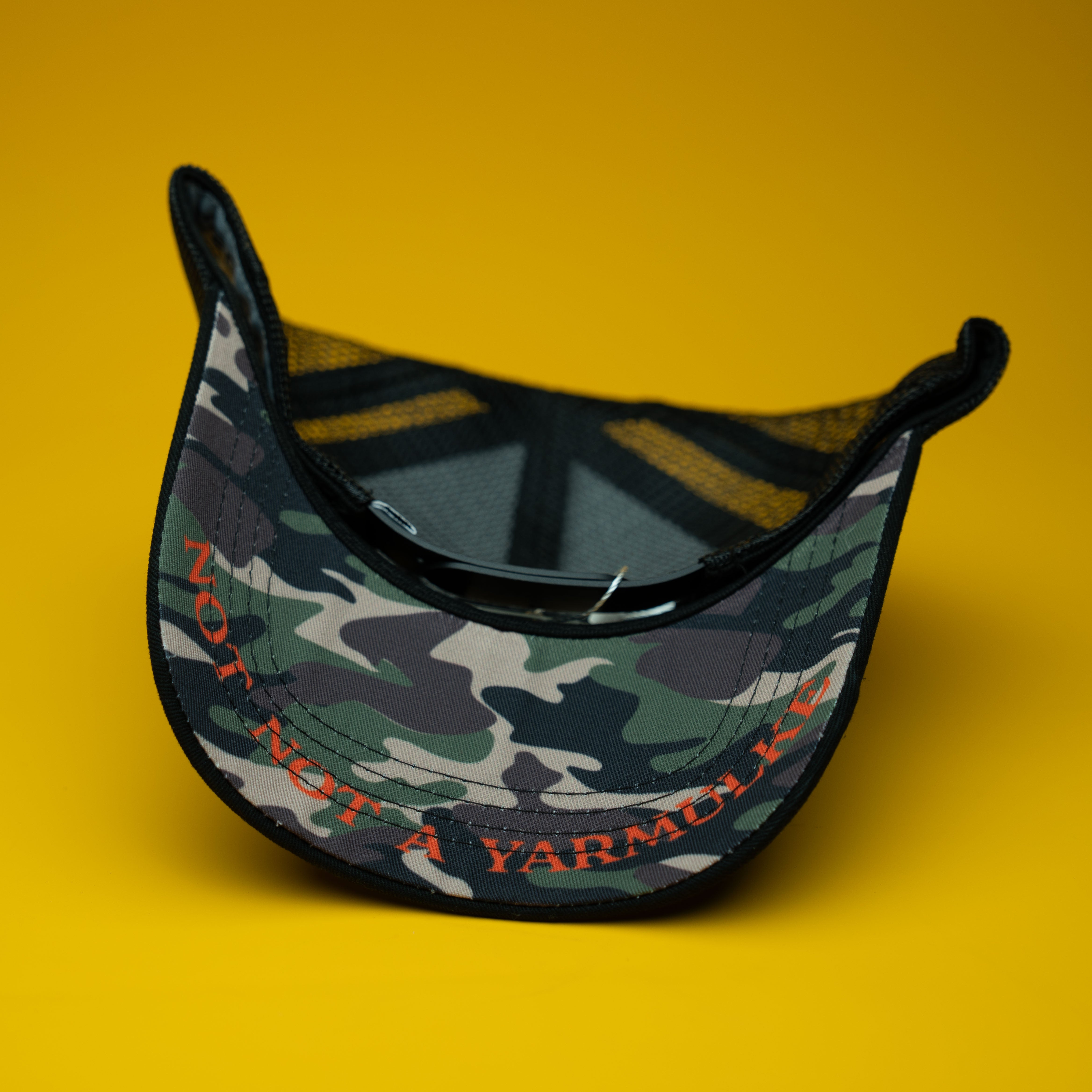 Camouflage cap with text on a yellow background