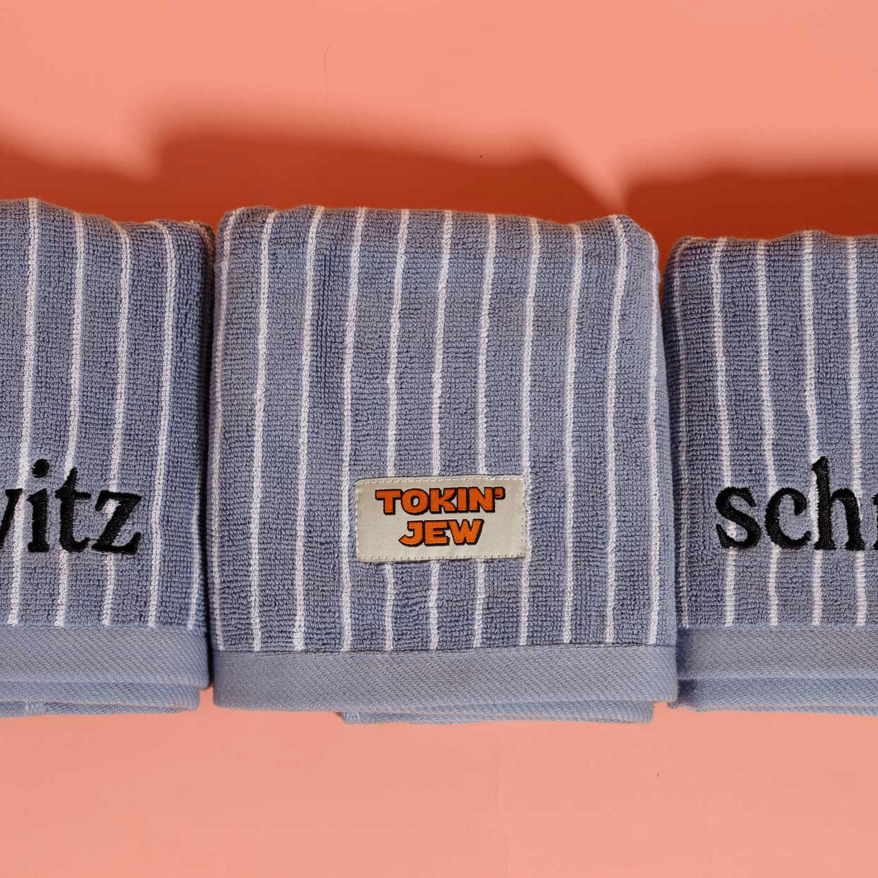 Three striped towels with embroidered words on a peach background