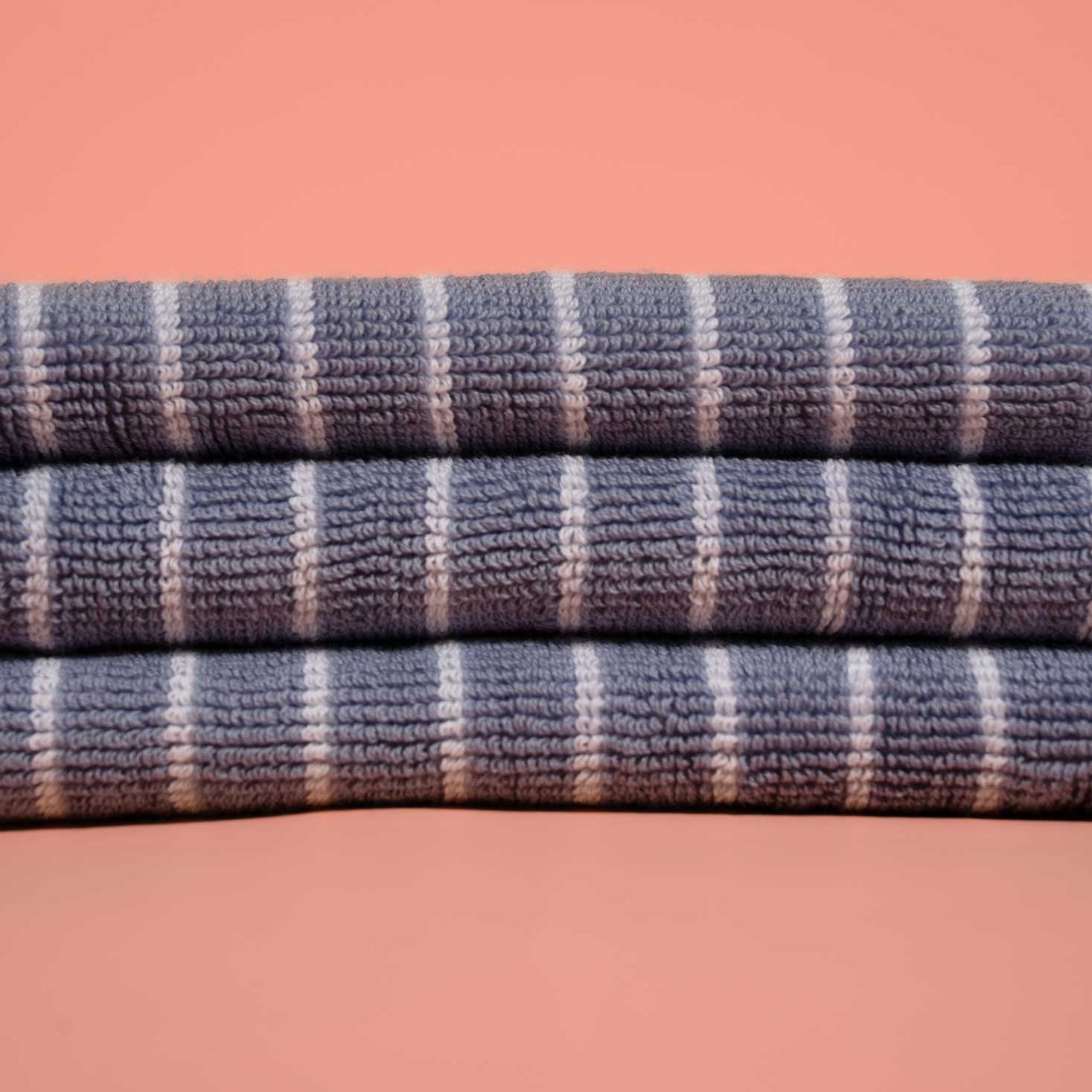 Stack of blue and white striped towels on a pink background