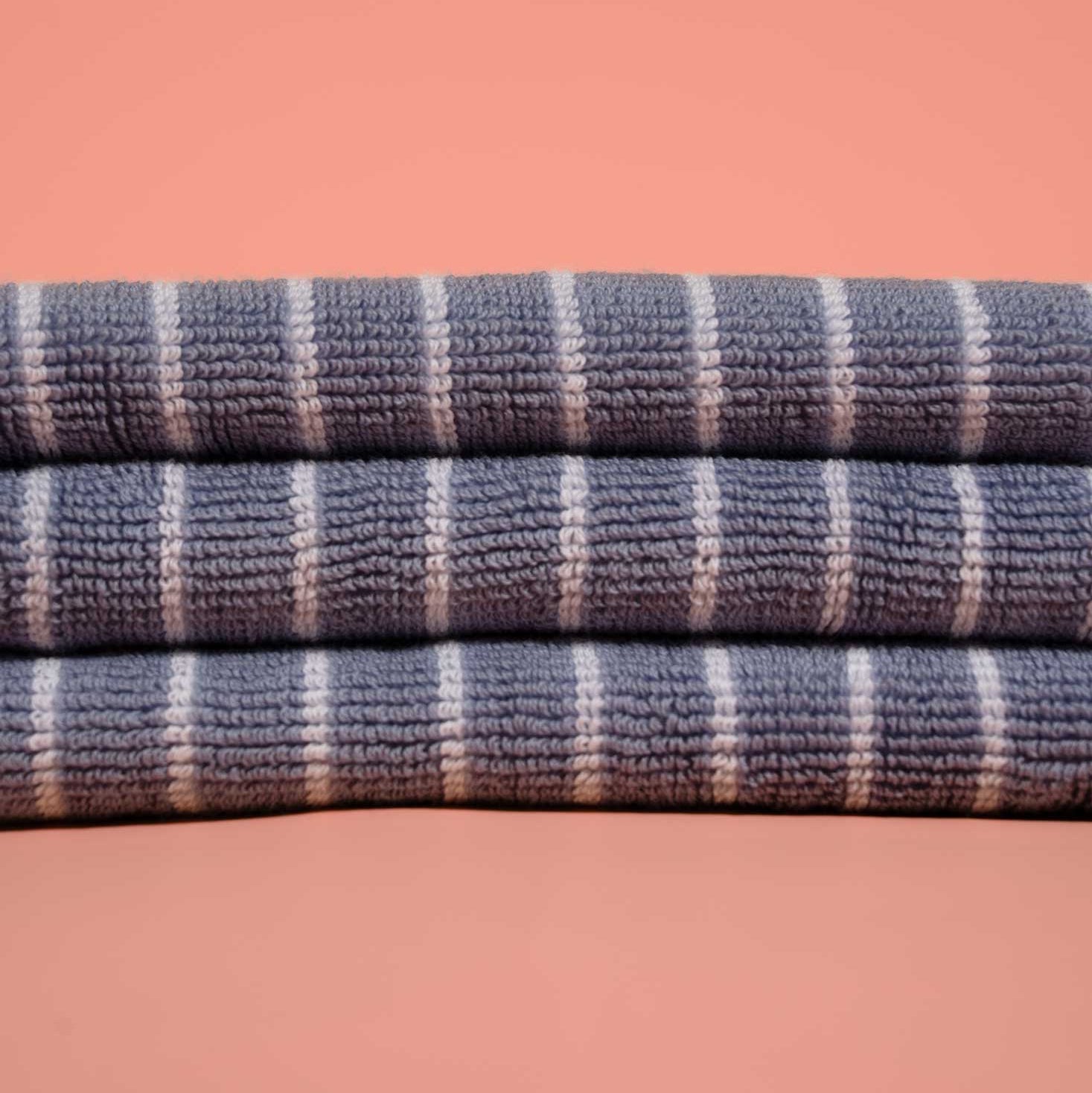 Stack of blue and white striped towels on a pink background