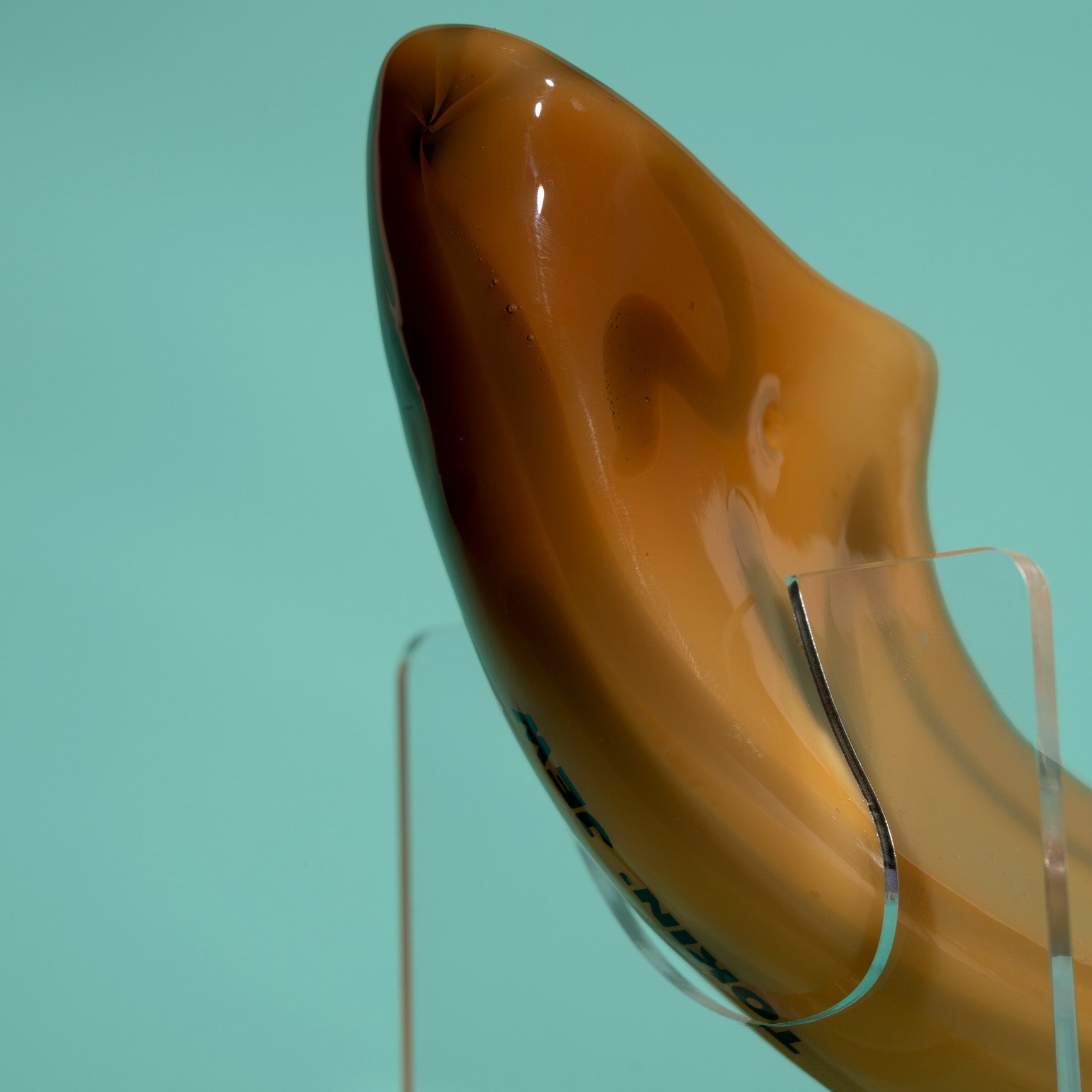Shofar on a clear stand against a teal background