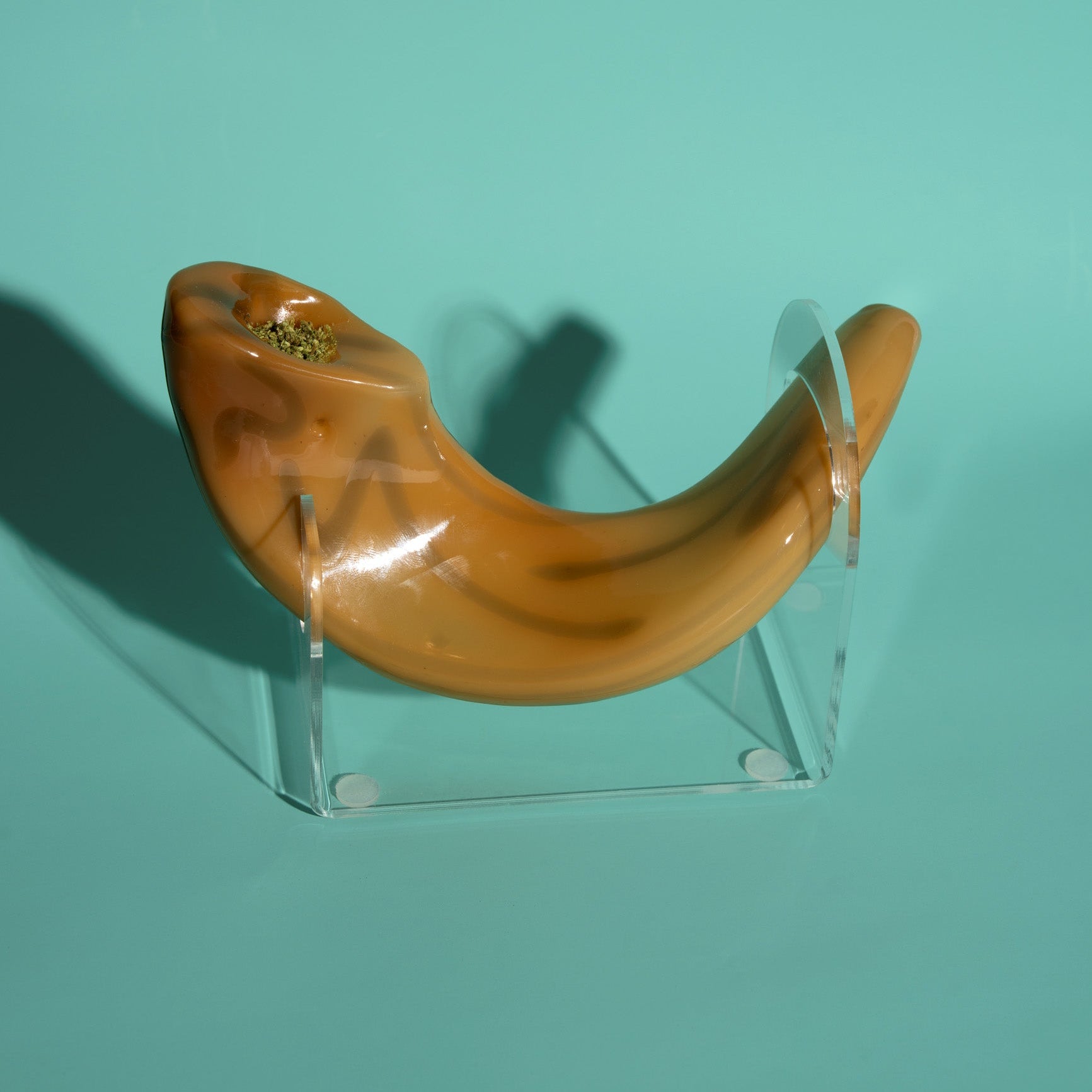 Shofar on a clear stand against a teal background