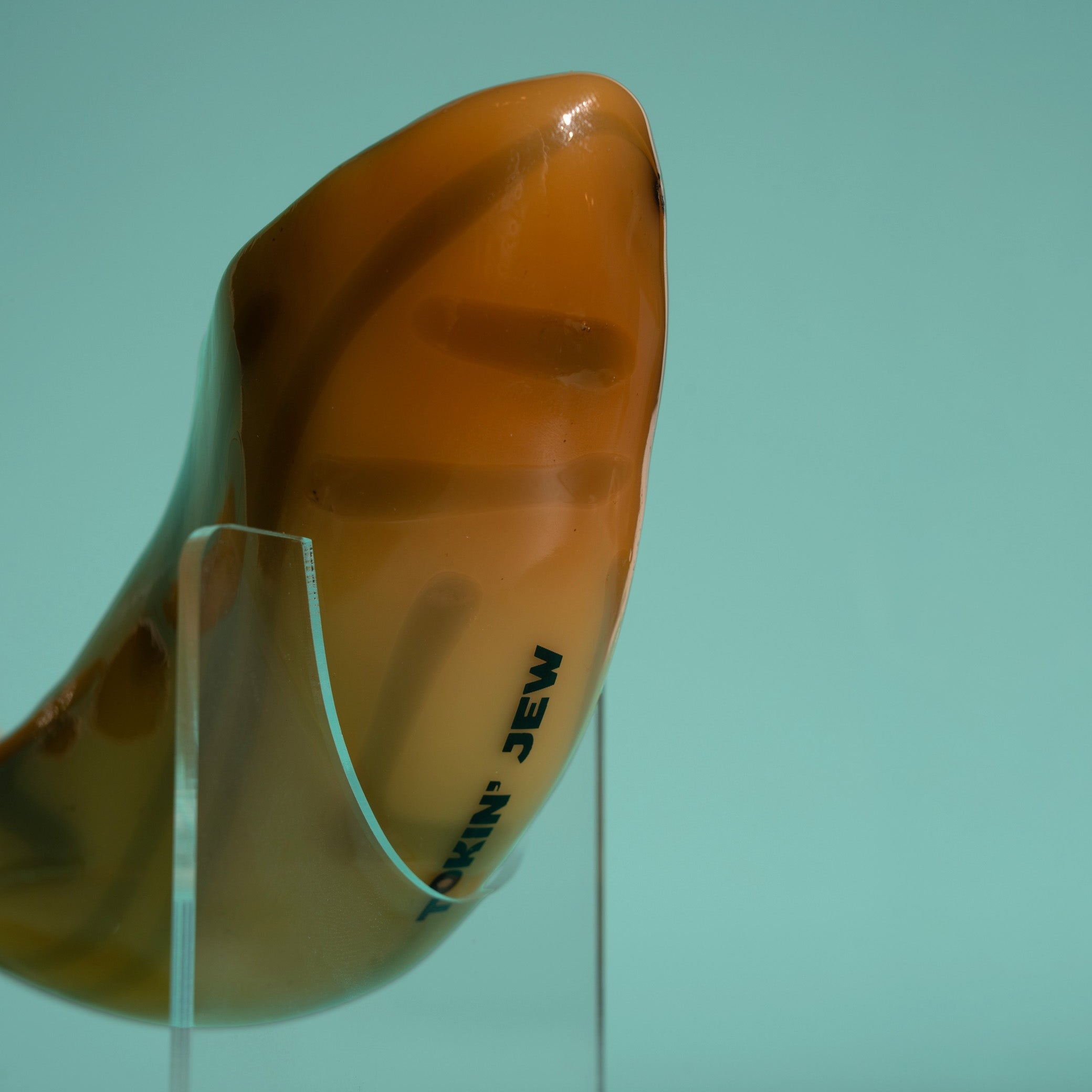 Shofar on a clear stand against a teal background