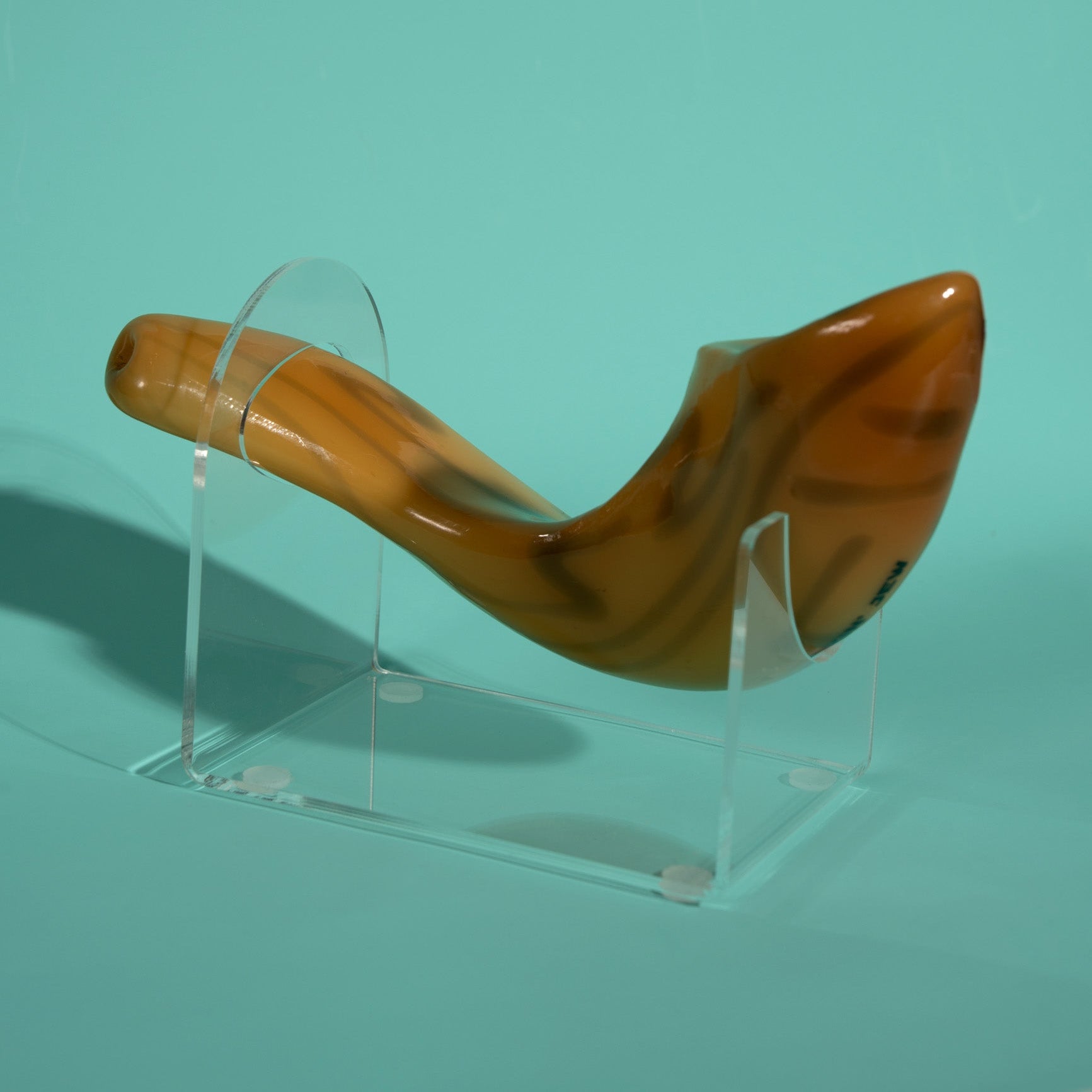 Wooden shofar on a clear stand against a teal background