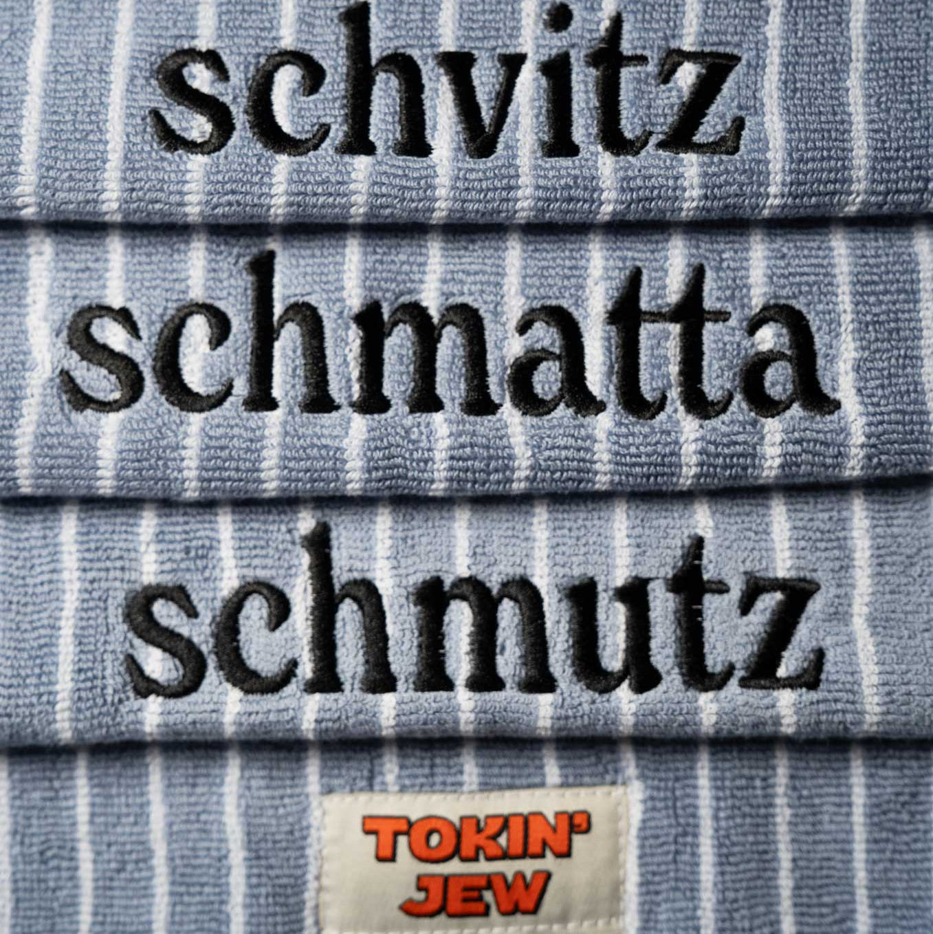 Stack of folded towels with embroidered text and a 'Tokin' Jew' brand label.