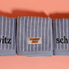 Three striped towels with embroidered words on a peach background