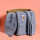 Folded blue striped towels with 'Tokin' Jew' branding on a pink background