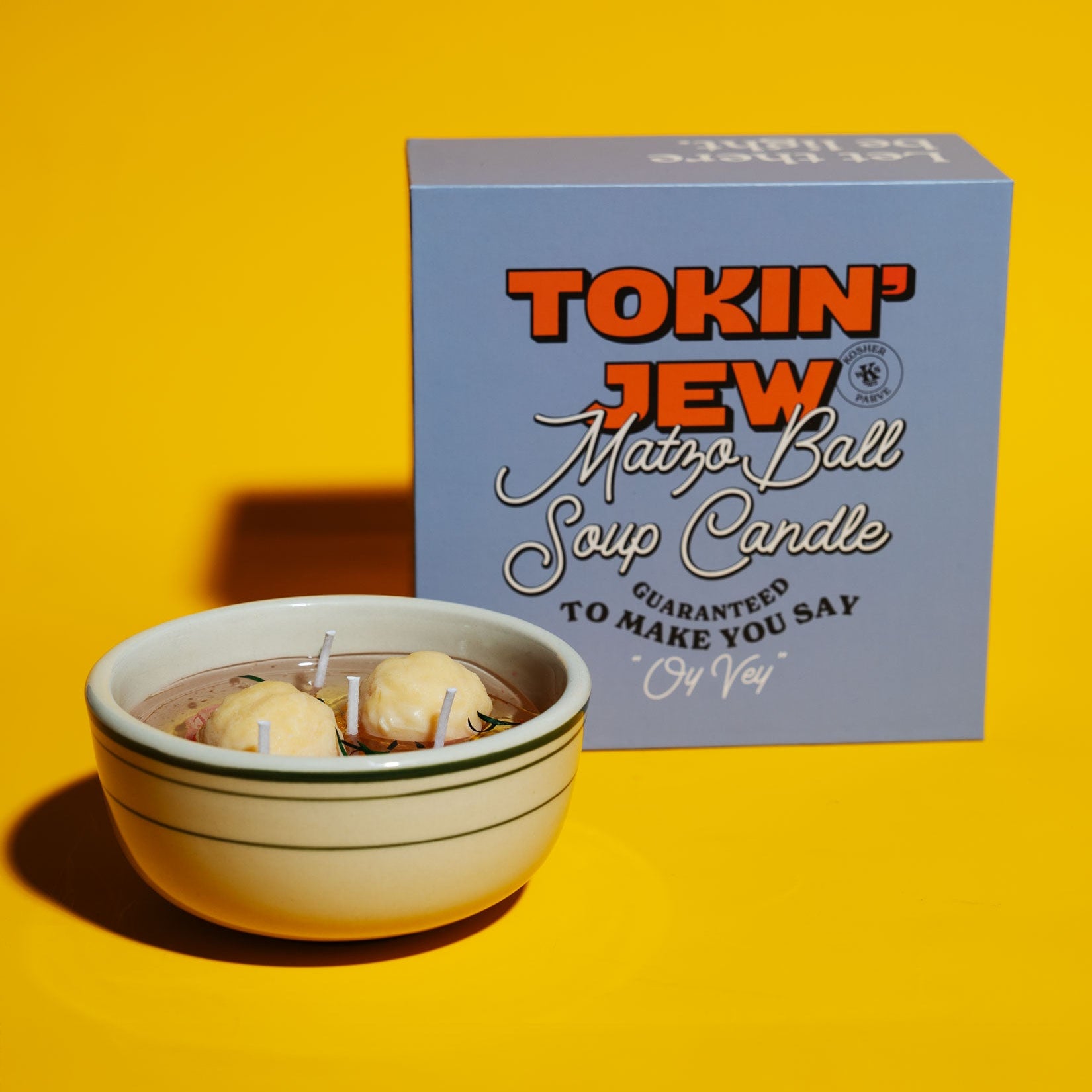 Matzo ball soup candle in a bowl with packaging labeled 'Tokin' Jew Matzo Ball Soup Candle' on a yellow background.