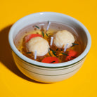 Matzo ball soup candle on a yellow background.