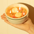 Hand holding a matzo ball soup candle against a beige background