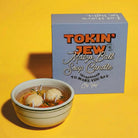 Matzo ball soup candle in a bowl with a box labeled 'Tokin' Jew Matzo Ball Soup Candle' on a yellow background