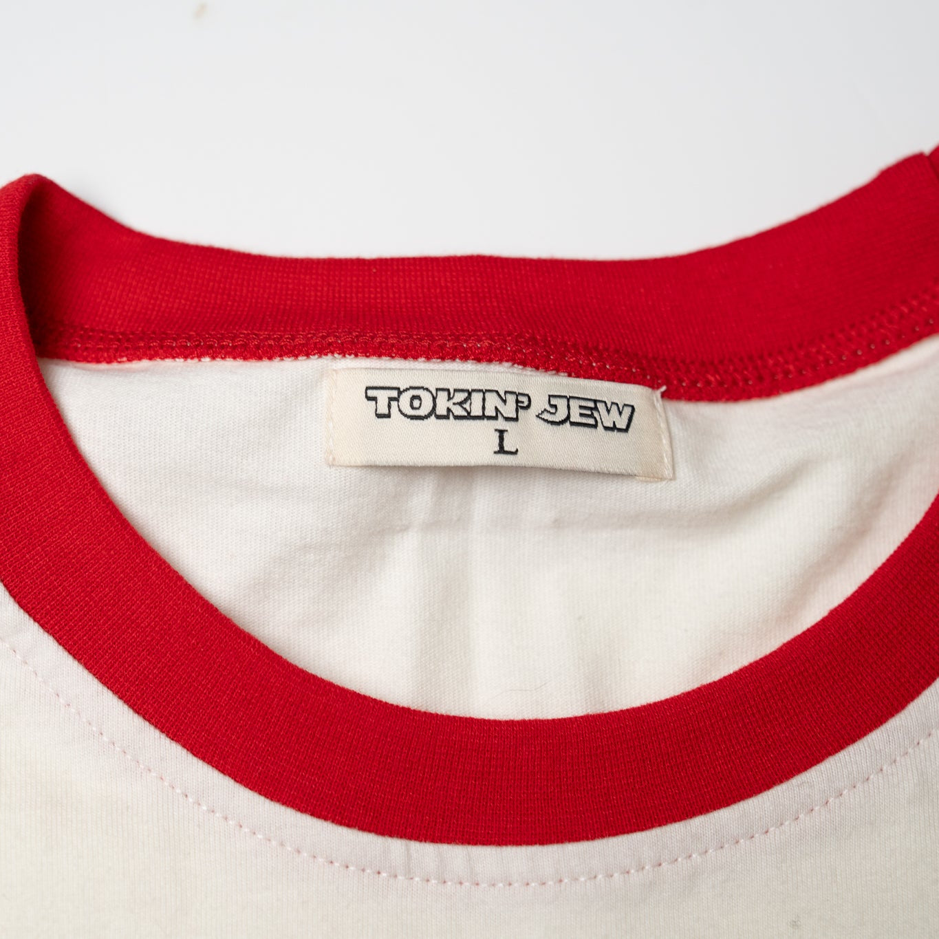 Close-up of a white shirt with red collar and 'Tokin Jew' label on a white background