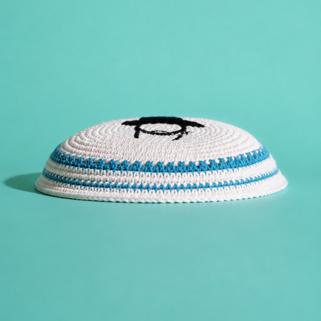 A white knit kippah with blue stripes and a black embroidered Rabbi on top, set against a solid teal background.
