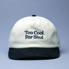 White cap with black text 'Too Cool For Shul' on a light gray background